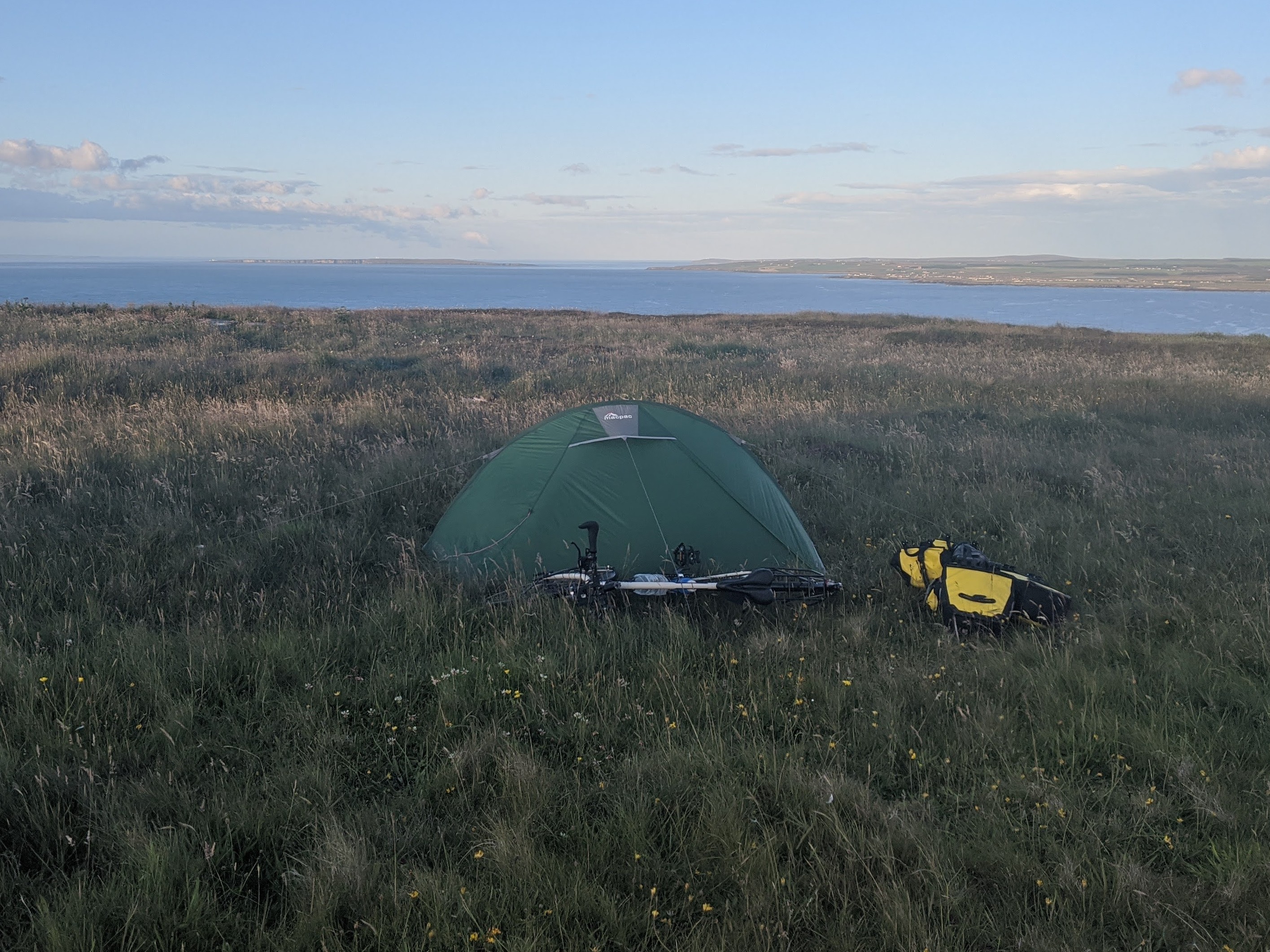 Green tent on coast with sunset backdrop